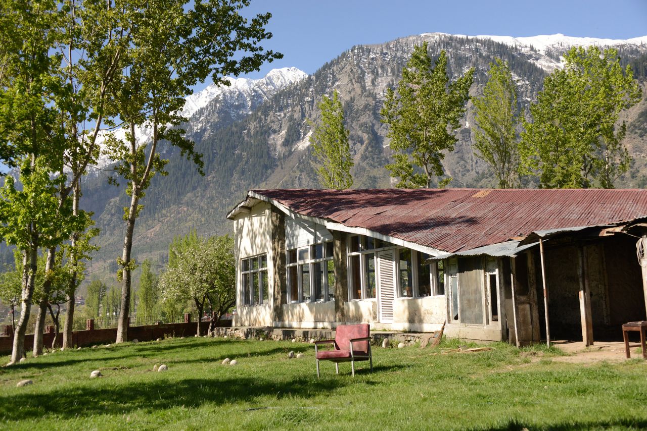 Scenic view of an abandoned bungalow surrounded by lush nature and mountains.