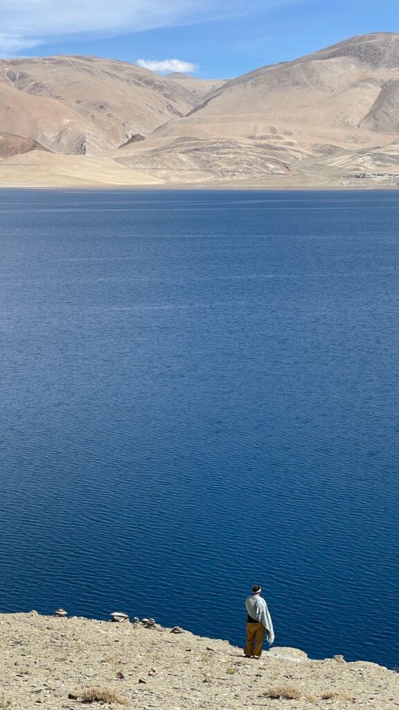 A lone traveler gazes at the serene blue waters of Pangong Lake in Ladakh, India.