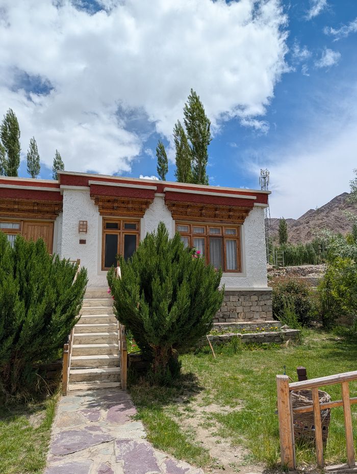 Charming traditional house in Leh with stone steps and vibrant green shrubs.